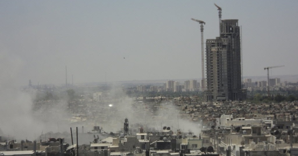 14.jul.2012 - Fumaça é vista em local bomardeado na região de Homs, na Síria