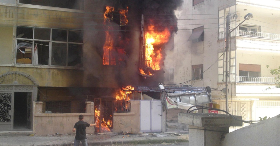 18.jul.2012 - Prédio pega fogo nesta quarta-feira (18) após bombardeio no distrito de Al-Ghouta, em Homs, na Síria