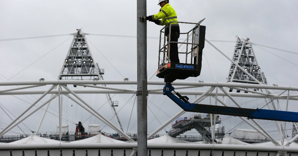 Trabalhador faz ajustes em poste na frente do estádio do Parque Olímpico de Stratford na quarta-feira (18/07)