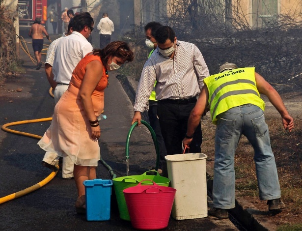 19.jul.2012 - Bombeiros ajudam moradores durante incêndio florestal nesta quinta-feira (19), que pode atingir casas do vilarejo de Camacha, nas montanhas da cidade de Funchal, na ilha portuguesa da Madeira