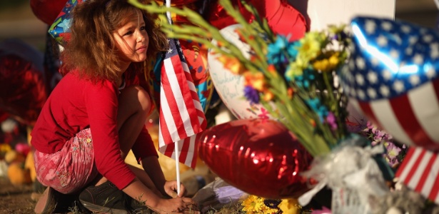 Criança coloca uma bandeira dos Estados Unidos em memorial improvisado para as vítimas do tiroteio em cinema em Aurora, Colorado (EUA) (22/7/12) - Chip Somodevilla / Getty Images / AFP