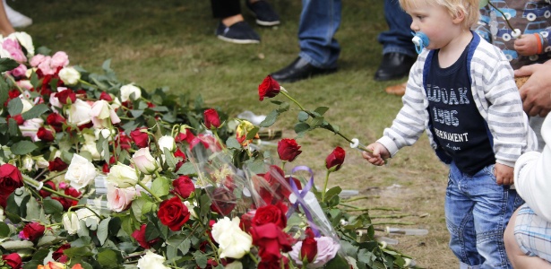 Criança coloca flor vermelha sobre monte de flores em homenagem às vítimas do ultradireitista Anders Behring Breivik, em cerimônia realizada no último domingo (22), quando os ataques completaram um ano