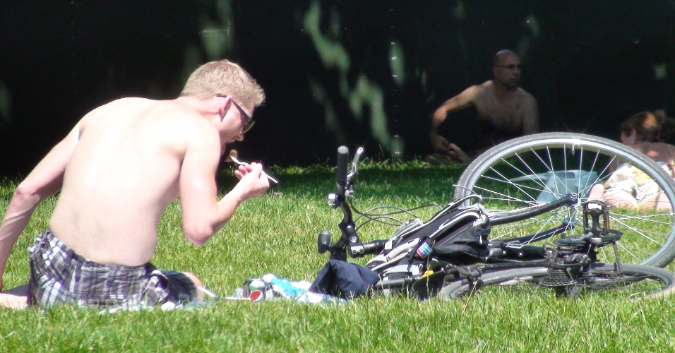 Ciclista faz lanche e toma sol no Hyde Park, local por onde passarão competições de ciclismo, triatlo e maratona aquática