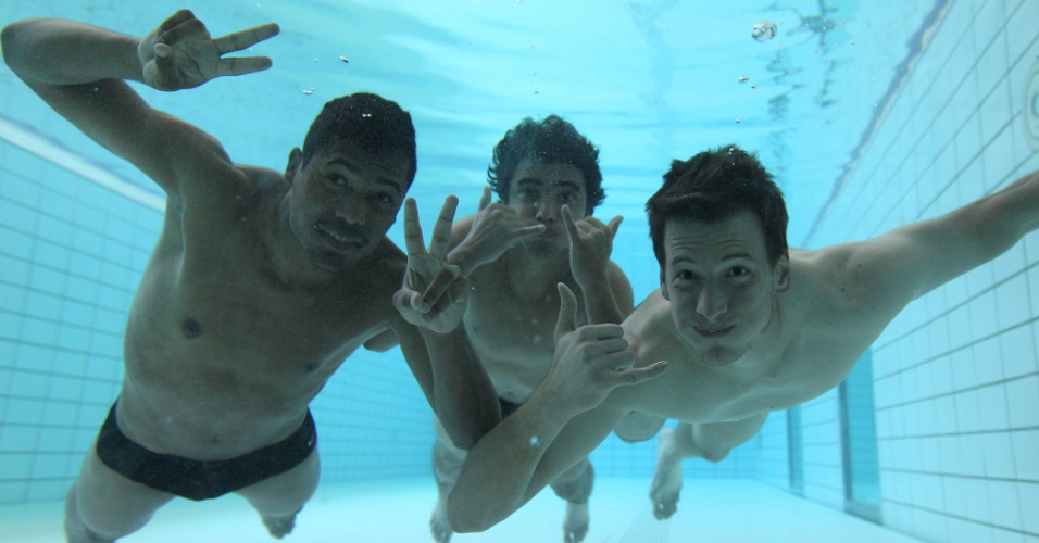 Os laterais Alex Sandro (esq.) e Rafael e o goleiro Neto brincam com a câmera do fundo da piscina em que a seleção trabalhou nesta terça-feira, em Londres