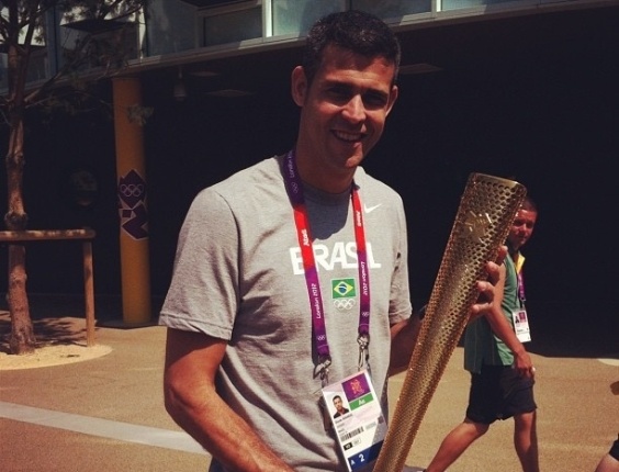 Dante, atleta da seleção masculina de vôlei tira foto segurando a tocha dos Jogos Olímpicos de Londres