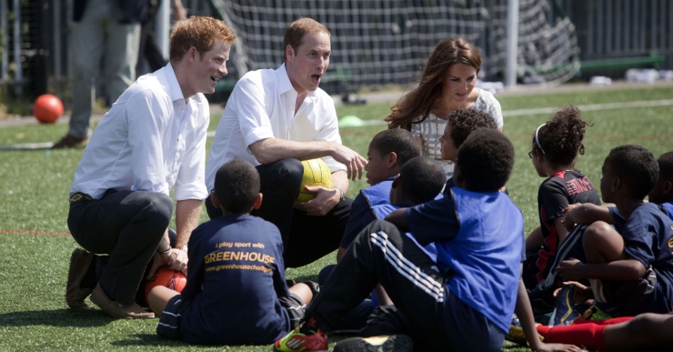 Harry (e), William (c) e Kate conversaram com as crianças do colégio Bacon durante visita para lançamento de um programa de treinadores