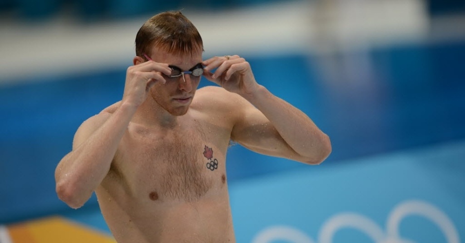 Nadador exibe aros olímpicos e imagem símbolo do Canadá em tatuagem no peito, durante treino em Londres
