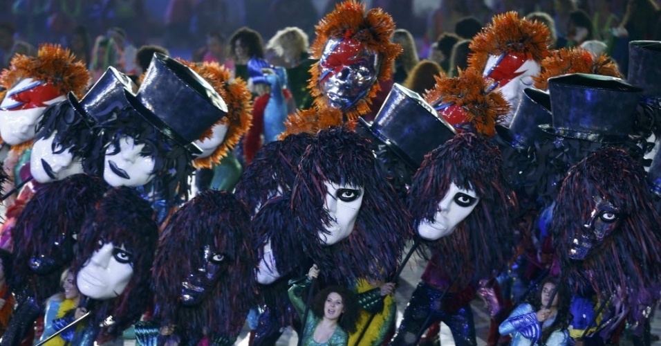 Artistas carregam máscaras representativas dos astros do rock inglês durante cerimônia de abertura