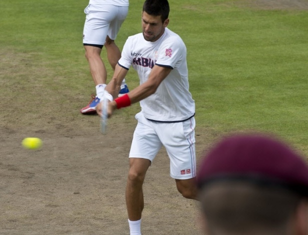 O tenista sérvio Novak Djokovic treina sob os olhares de soldados britânicos em Wimbledon (27/07/2012)