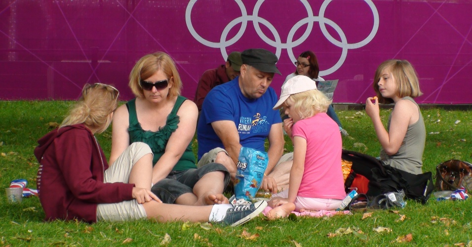 Pessoas descansam em gramado perto de local olímpico no Saint James Park à espera da final do ciclismo de estrada