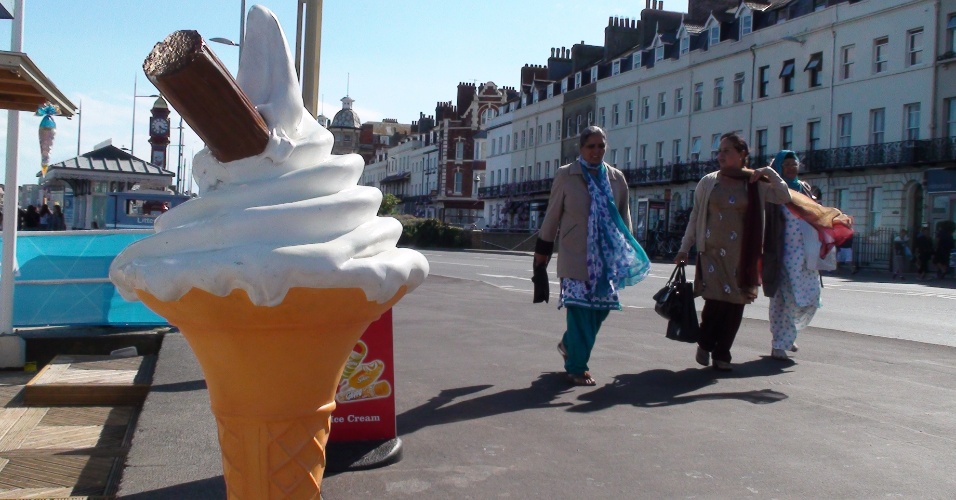 Família muçulmana passeia por calçadão de Weymouth e passa diante de sorveteria local