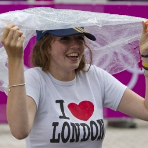 Mulher com camiseta "Eu amo Londres" se cobre para fugir da chuva na capital britânica - Neil Hall/Reuters