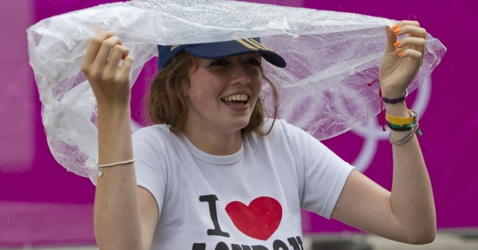 Garota com camiseta "Eu amo Londres" se cobre para fugir da chuva deste domingo