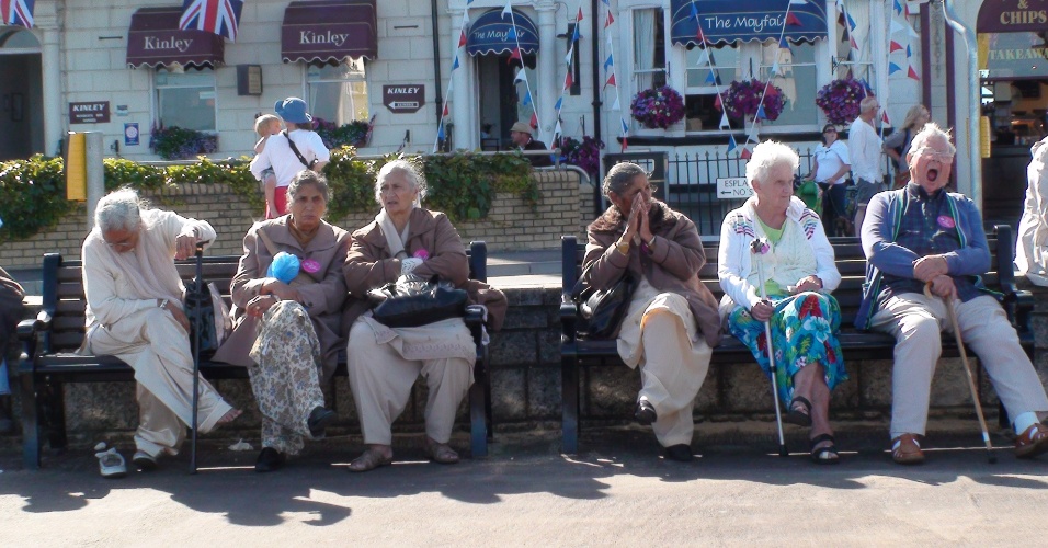 Grupo de idosos observa o movimento no calçadão de Weymouth durante o entardecer na sede olímpica do iatismo