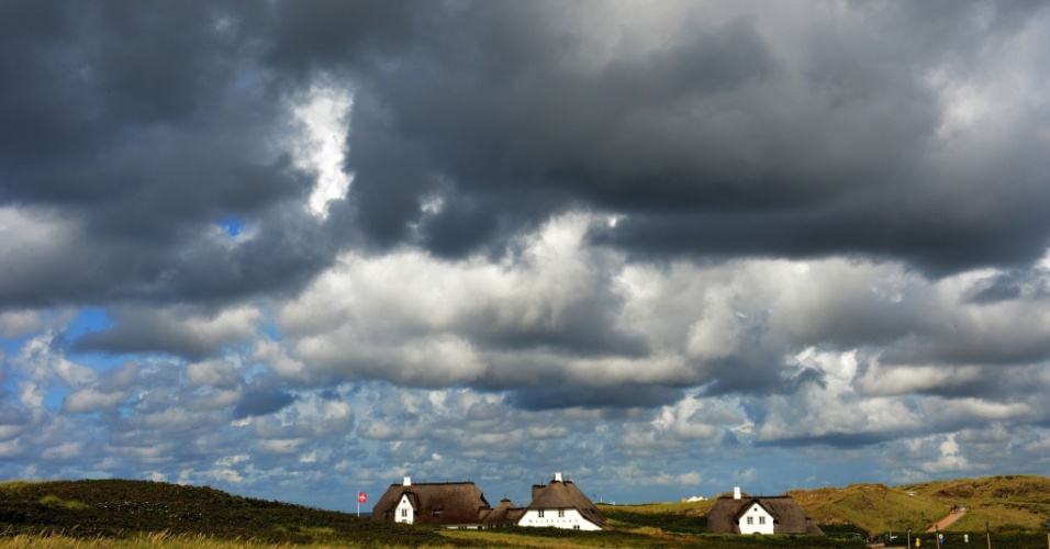 30.jul.2012 Nuvens negras pairam sobre casas de palha em Kampen, na ilha de Sylt, no Mar do Norte, na Alemanha