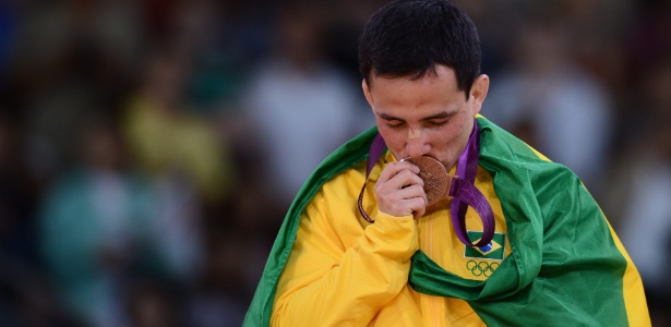 Enrolado na bandeira brasileira, Felipe Kitadai beija a sua medalha de bronze 