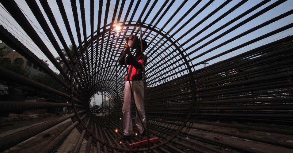 01.ago.2012  - Homem solda barras de ferro para fazer um pilar em construção de uma ponte em Lahore, no Paquistão