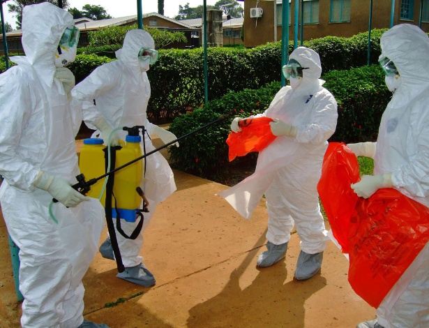 Foto de 28 de julho mostra equipe da  OMS (Organização Mundial da Saúde) vestindo roupa de proteção para entrar em hospital de Uganda; país africano vive surto da doença, que causa febre hemorrágica - AFP/Isaac Kasamani 