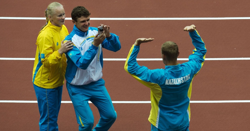 Atletas do Cazaquistão tiram fotos em frente à pira olímpica no Estádio Olímpico