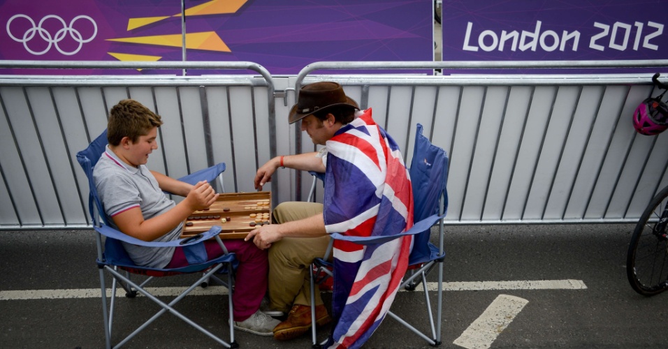 Torcedores britânicos jogam partida de gamão, aguardando o início da prova do ciclismo contra o relógio