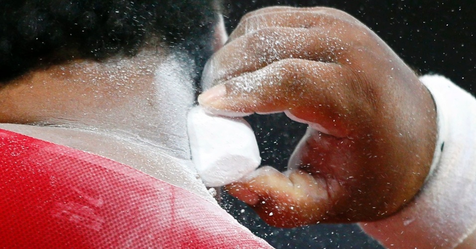 Norte-americano Reese Hoffa aplica resina em pó sobre o pescoço durante final do arremesso de peso