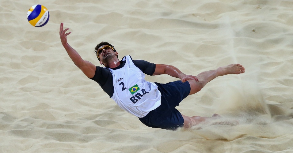 Pedro Cunha, dupla de Ricardo, salta para defender bola em partida contra dupla da Espanha pelas oitavas de final do vôlei de praia