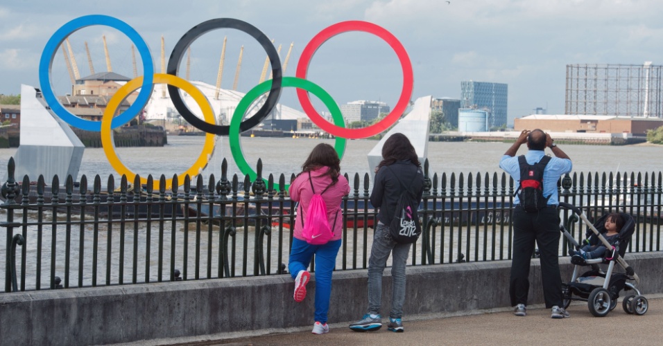 Público fotografa anéis olímpicos colocados sobre o Rio Tâmisa