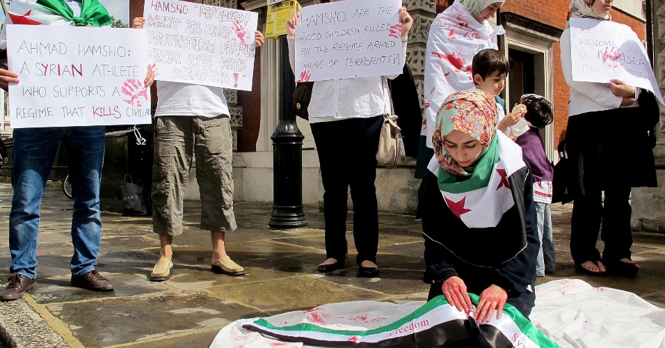 Vestidos com roupas com as cores da bandeira síria, imigrantes sírios que vivem na Inglaterra pediam que torcedores entrassem na arena do hipismo com selo grudado que pedia liberdade para o país