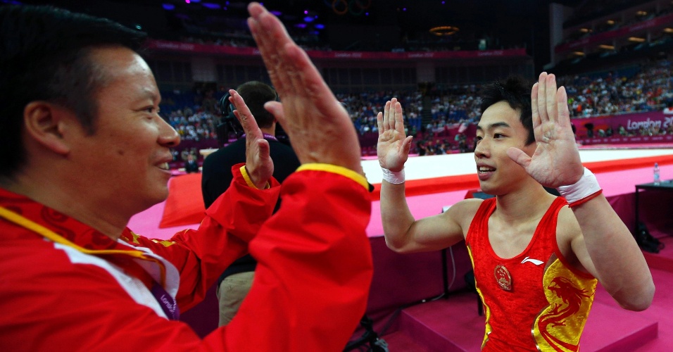 Chinês Zou Kai comemora com seu técnico ao conquistar a medalha de ouro da final de solo neste domingo em Londres