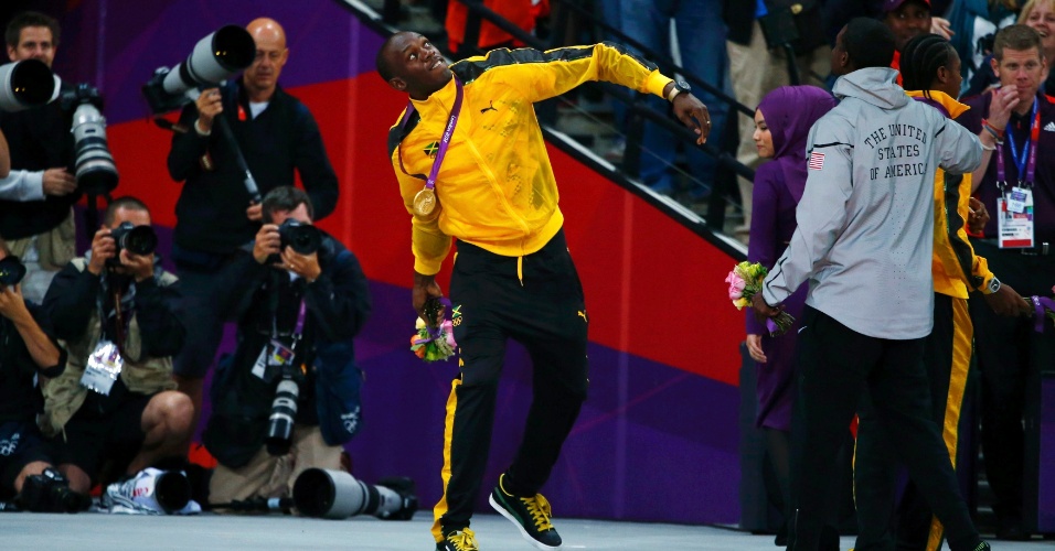 Medalhista de ouro Usain Bolt joga para o ar buquê de flores, após cerimônia de premiação dos 100 m rasos dos Jogos de Londres