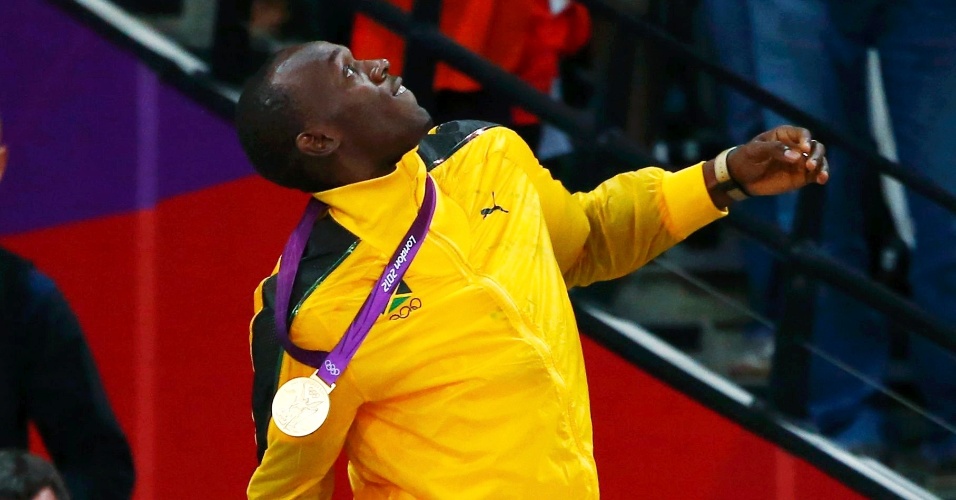 Usain Bolt arremessa para o ar buquê de flores recebido após cerimônia de premiação dos 100 m rasos