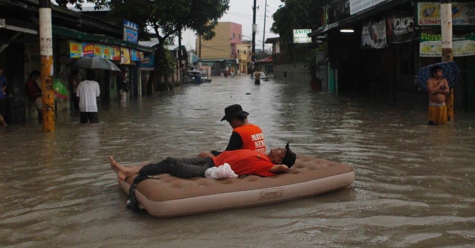 7.ago.2012 - Equipes de resgate descansam em colchão inflável em cidade da região metropolitana de Manila, nas Filipinas, nesta terça-feira (7). Desde o início das fortes chuvas no país, 53 pessoas morreram
