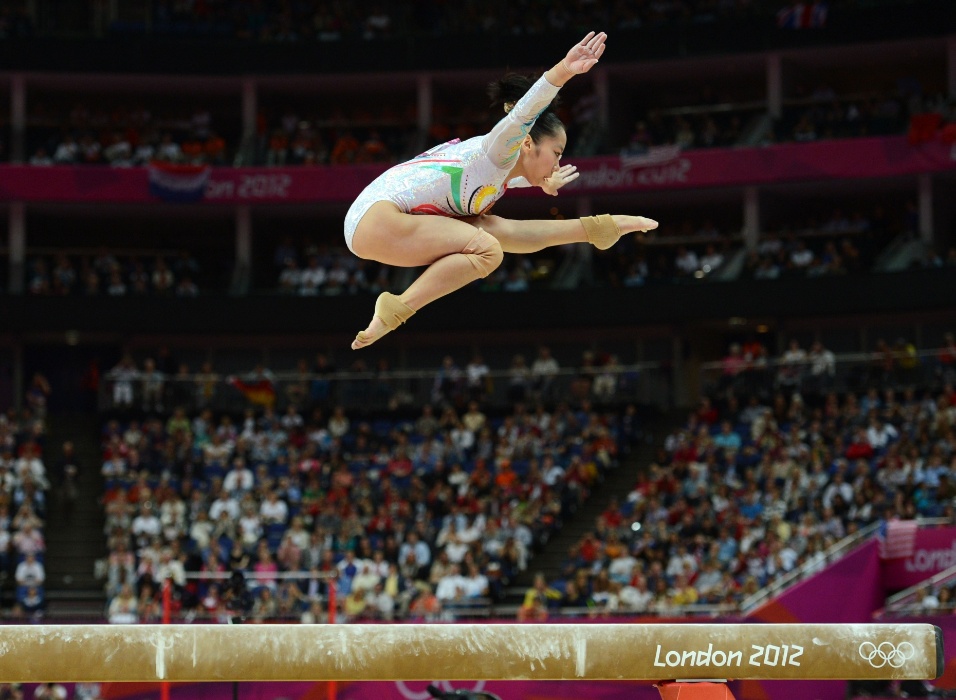 Chinesa Deng Linlin faz um alto salto coreográfico durante sua série na trave; a asiática levou a medalha de ouro na prova