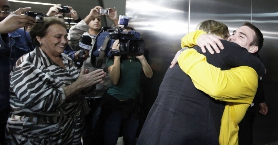 Arthur Zanetti abraça a mãe Roseane na chegada ao aeroporto, enquanto a avó (à esq.) aplaude o neto medalhista de ouro