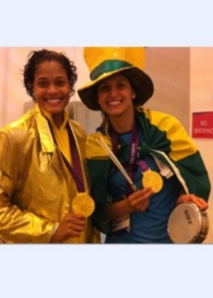 Adenízia e Dani Lins tiram foto usando a medalha de ouro conquistada na final do vôlei feminino.