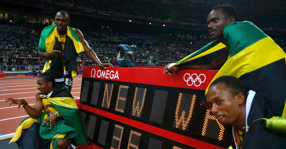 Equipe jamaicana do revezamento 4x100 m comemora medalha de ouro e novo recorde mundial ao lado de marca