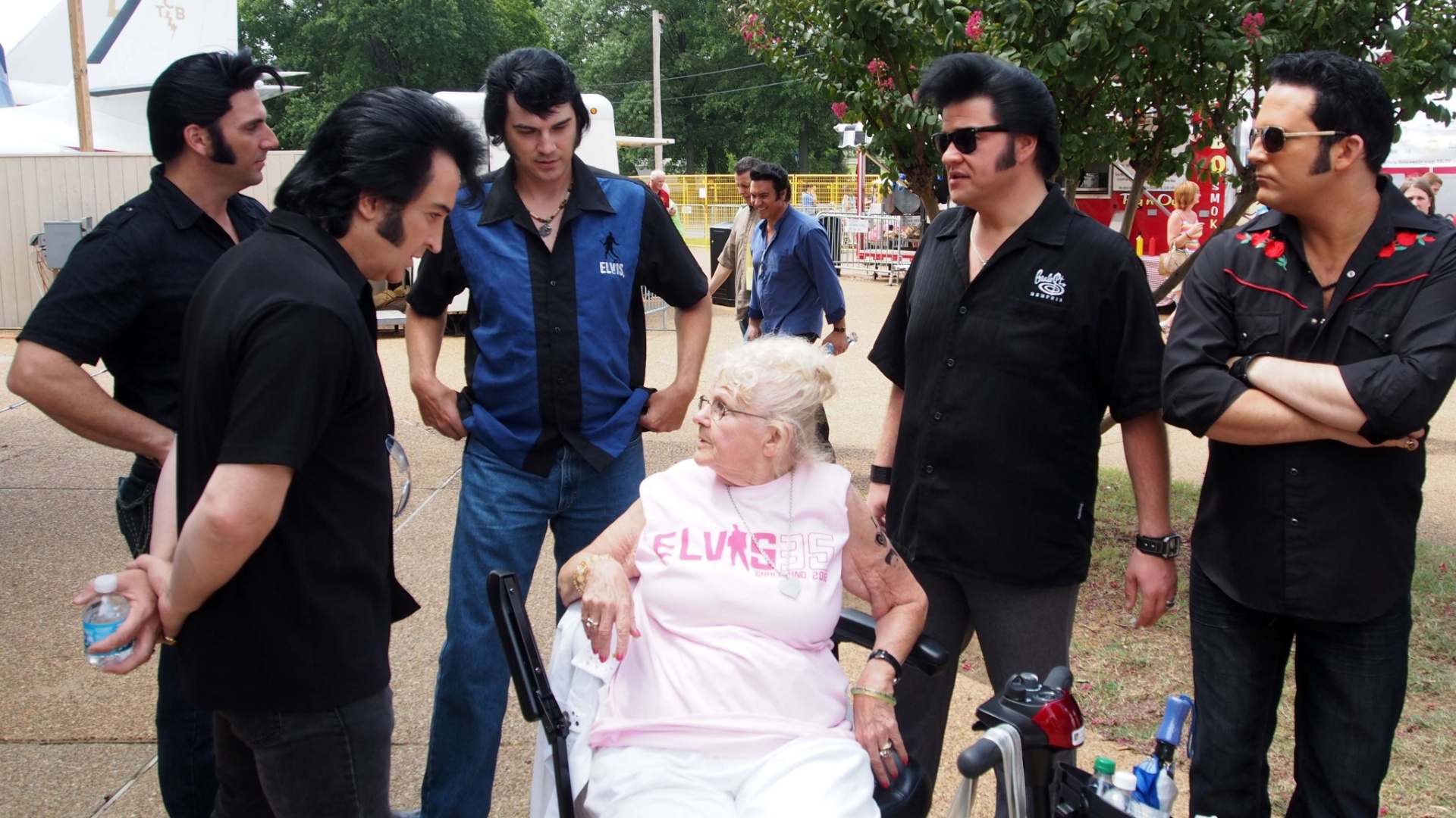 Sósias de Elvis Presley em volta de uma fã do cantor em Gracelando durante a Elvis Week (14/8/12) - Robert MacPherson/AFP