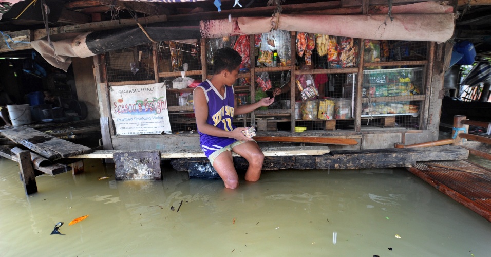 15.ago.2012 - Menino faz compras em uma loja flutuante em Manila, capital das Filipinas. Quatro pessoas morreram depois que outra tempestade tropical, batizada de Kai-tak, atingiu o país