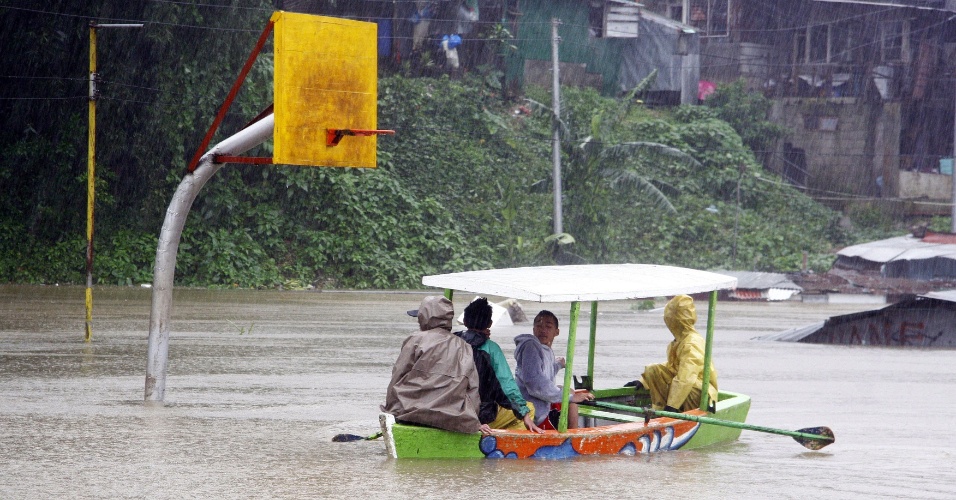 15.ago.2012 - Moradores da província de Trinidad, no norte de Manila, capital das Filipinas, navegam em quadra esportiva alagada pela tempestade tropical Kai-tak, nesta quarta-feira (15) 