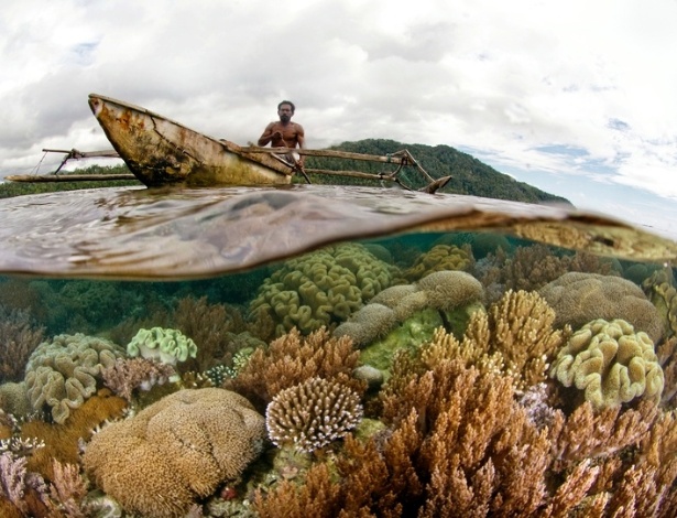 Homem passa de barco sobre os corais e os recifes da costa de Raja Ampat, na Indonésia - Sterling Zumbrunn/Conservation International