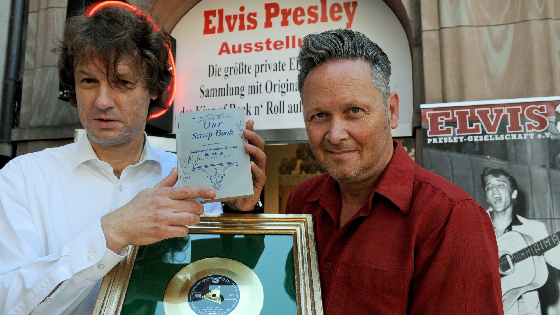 Os colecionadores alemães Torsten Meck (à esquerda) e Andreas Schröer exibem as última aquisições para o Museu Elvis Presley: um livro de músicas e um disco de ouro pela música "Hound Dog". Localizado em Dusseldorf, na parte oeste da Alemanha, o local reúne a maior coleção de artigos do cantor fora dos Estados Unidos - Horst Ossinger / AFP Photo