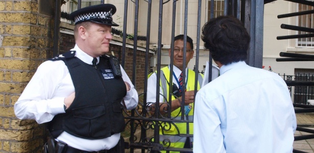 Observado por um policial, ativista da Anistia Internacional entrega a um guarda da Embaixada Russa em Londres uma petição em apoio às integrantes da banda punk Pussy Riot (16/8/2012) - Max Nash/AFP PHOTO