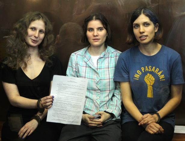 Nadezhda Tolokonnikova (à esq.), Maria Alyokhina e Yekaterina Samutsevich (à dir.), do grupo punk Pussy Riot, exibem o veredito após serem senteciadas a dois anos de prisão, no tribunal, em Moscou (17/8/12) - AP