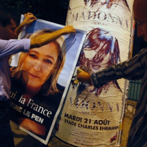 Ativistas de direita da Frente Nacional cobrem um pôster da cantora Madonna com um cartaz da líder do partido, Marine Le Pen  - Eric Gaillard/Reuters