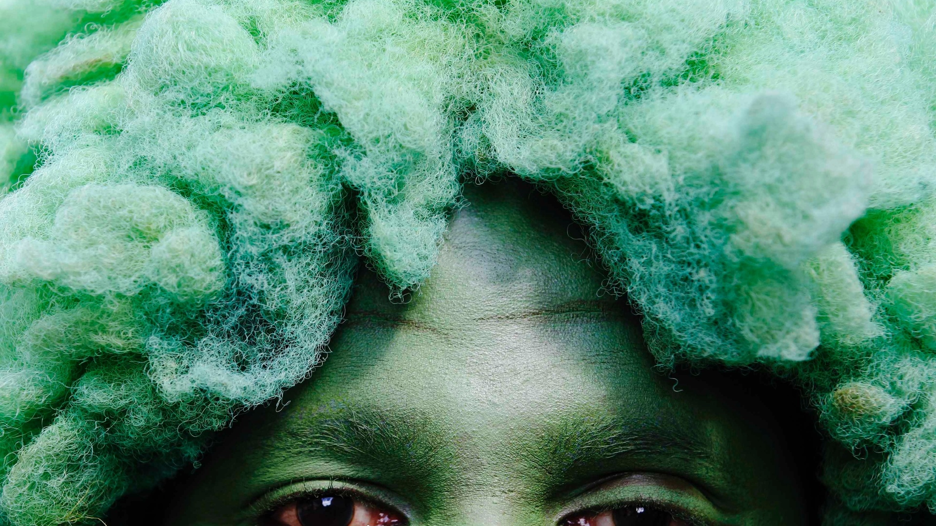 26.ago.2012 - Folião de peruca e o rosto pintado de verde durante o festival de Notting Hill, em Londres. O evento é inspirado em festas do Caribe é considerado o maior carnaval de rua da Europa - Luke Macgregor/Reuters
