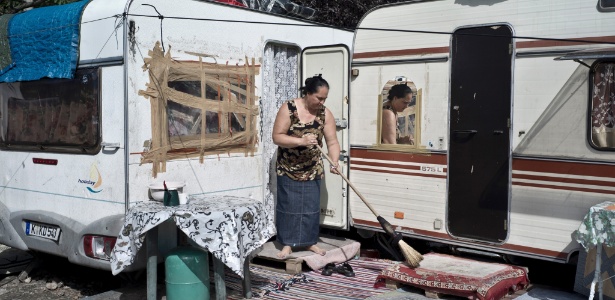 Mulher limpa área exterior a trailer em acampamento cigano em La Courneuve, na França - Corentin Fohlen/The New York Times