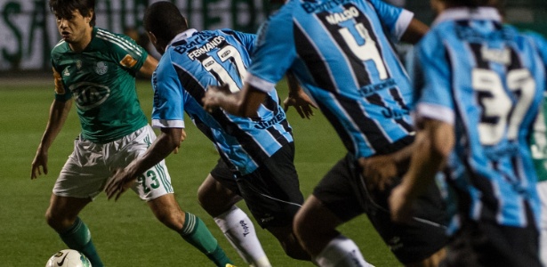 Tiago Real caminha com bola e sofre marcação de Fernando, do Grêmio - AFP PHOTO/Yasuyoshi CHIBA