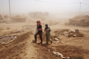 Casal carrega garrafas de água em meio a tempestade de areia em campo de refugiados na Jordânia