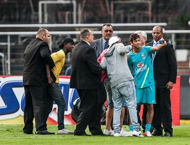 Neymar atende pedido dos torcedores que invadiram o campo e tira foto, enquanto seguranças esperam