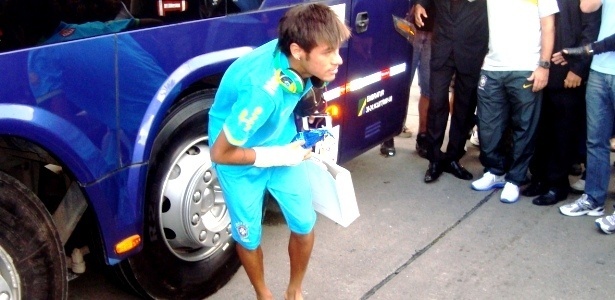 Neymar se abaixa para pegar os presentes atirados pelos fãs da seleção na porta do hotel em Recife